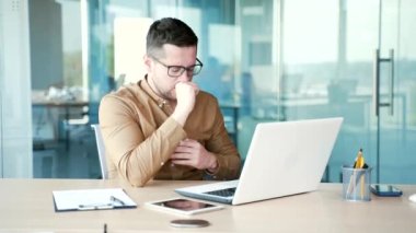 İş yerindeki iş yerinde laptopta çalışırken öksüren hasta genç işadamı. Üşütmüş ya da grip olmuş bir erkek elini göğsüne dayamış. Bronşiti var.