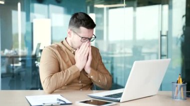 Hasta işadamı, bir iş yerinde çalışırken dizüstü bilgisayarla çalışırken burnunun akmasından muzdarip. Üzgün erkek burnunu mendille siler. İnsanda soğuk algınlığı, virüs ya da grip var.