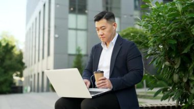 Resmi takım elbiseli Asyalı işadamı ofis binasının yakınındaki bir bankta oturan bir dizüstü bilgisayarla çalışıyor. Kulaklıklı serbest çalışan bir öğretmen ve elinde bir fincan kahveyle bilgisayarda daktilo yazıyor.