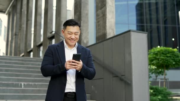 Empresário Sorridente Terno Formal Está Usando Smartphone Enquanto Caminha Rua — Vídeo de Stock