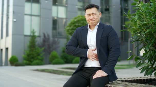 Empresário Asiático Perturbado Terno Formal Sente Dor Estômago Sentado Banco — Vídeo de Stock
