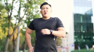 Yetişkin bir Asyalı koşucu, şehir caddesindeki bir park yolunda sabah koşusundan sonra nefes darlığı çekiyor. Siyah tişörtlü yorgun bir sporcu dizlerinin üzerine çöker ve derin derin nefes alır. Spor ve dayanıklılık kavramı