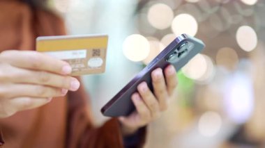 Kadın eli akıllı telefon ve kredi kartını kapalı bir alışveriş merkezinde tutuyor. Noel için internetten kadın alışverişi Noel indirimi, indirimi ve kapalı mekanlı terfiler.