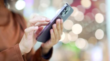 Kapalı alan alışveriş merkezindeki Bokeh 'le akıllı telefon iletişimini kullanarak kadın elini kaybet. Kadınlar Noel indirimi için internet mağazası kullanıyor, cep telefonu kullanarak satış promosyonları yapıyor.