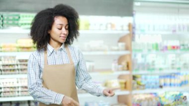 Marketteki bir satıcı, reklam için boş bir yere parmağıyla işaret eder. Bir süpermarkette kameraya bakan Afrikalı Amerikalı kadın çalışan ya da küçük işletme sahibi kopyala