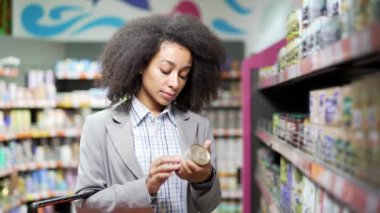 Kadın, ürün ürünlerinin bileşimini inceler. Market araştırmalarında konserve konservelerin üzerinde kadın müşteri etiketi okur ve bilgi okur. Markette seçimler yapanlar