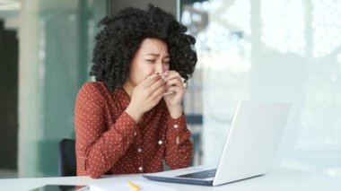 Genç üzgün Afro-Amerikan bayan çalışanı ofiste oturan bir dizüstü bilgisayarla bir psikologla görüntülü görüşme yapıyor. Siyahi bir kadın online danışma sırasında ağlıyor, işyerindeki sorunlarını anlatıyor.