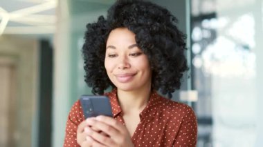 Mutlu, heyecanlı, genç, Afro-Amerikan bayan çalışanı iş telefonunda harika haberler okuyor. Siyahi kadın zaferi kutlar, sevinir, gülümser, jest yapar evet, zafer, vay canına. Kapat.