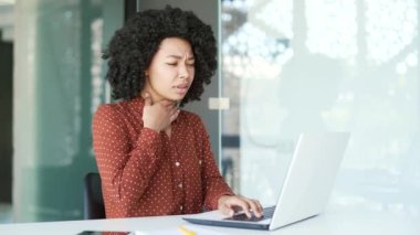 Ofiste dizüstü bilgisayarla çalışırken boğazı ağrıyan genç, Afro-Amerikan kadın çalışan hasta. Siyah kadın nezle, virüs ya da grip olmuş. Üzücü işçi, hassas bir noktaya masaj yapıyor.