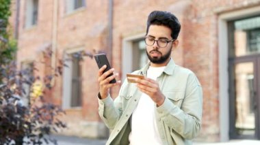 Gülümseyen yakışıklı sakallı öğrenci üniversite binasının yanındaki kampüs alanında duran bir akıllı telefondan kredi kartı numarasına giriyor. Genç bir adam internetten alışveriş yapıyor, indirimlerden ve terfilerden memnun.