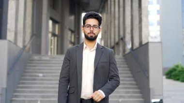 Resmi takım elbiseli mutlu genç bir iş adamının portresi bir ofis binasının yanında caddede duruyor. Gülümseyen yakışıklı girişimci kollarını kavuşturup kameraya bakıyor. Öğretmenin kafasından.