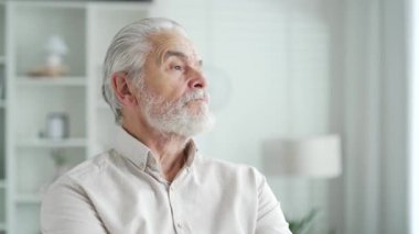 Evdeki parlak bir odada, koltukta oturan, gri saçlı, ciddi yaşlı bir adamın portresini yakından çek. Yakışıklı emekli erkek yan yana olduğunu düşünüyor. düşünceli olgun sakallı büyükbaba.