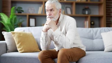 Yaşlı, yaşlı, kır saçlı bir adam evdeki oturma odasındaki kanepede oturan yalnızlık, can sıkıntısı ve depresyon hisseder. Yetişkin büyükbabamın sorunlarını düşünmesi beni üzüyor. Mutsuz ve hayal kırıklığına uğramış.