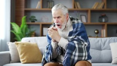 Yaşlı, yaşlı, gri saçlı, battaniyeyle kaplı adam evdeki oturma odasında kanepede otururken donmuştu. Yetişkin, emekli erkek, evde üşütmüş. Emekli büyükbaba düşük sıcaklıktan rahatsız oluyor.