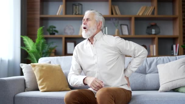 Zmęczony Starszy Siwy Mężczyzna Cierpiący Ból Pleców Siedzący Kanapie Salonie — Wideo stockowe