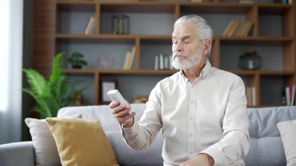 Starší Starší Muž Šedivými Vlasy Zapne Klimatizaci Dálkovým Ovládáním Který — Stock video
