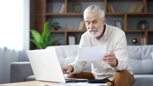 Senior Man Använder Ansökan För Att Spendera Räkningar Med Bärbar — Stockvideo