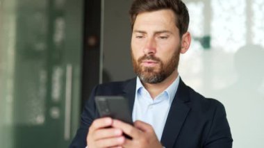 Resmi takım elbiseli bir işadamı iş yerindeki akıllı telefonu kullanıyor. İşçi mesajları okur ya da yazar, müşteriyle sohbet eder, telefon uygulamalarında bankacılık yapar, e-postaları kontrol eder, internette gezinir. Kapat.