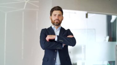 İş yerinde kollarını kavuşturmuş duran resmi takım elbiseli başarılı bir iş adamının portresi. İçerideki kameraya bakarak poz veren güler yüzlü, sakallı bir girişimci. Öğretmenin kafasından.