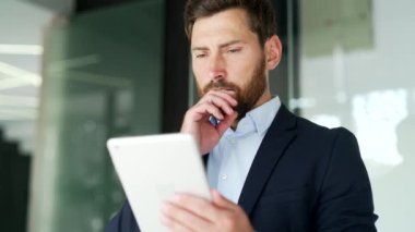 Resmi takım elbiseli iş adamı, iş yerinde ayakta duran dijital tablet kullanıyor. İşçi mesajları okur ya da yazar, bir müşteriyle sohbet eder, uygulama bankacılığı yapar, e-postayı kontrol eder ya da internette gezinir. Kapat.