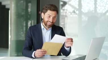 Resmi takım elbiseli mutlu iş adamı iş yerindeki masasında oturan harika haberlerle birlikte mektup okuyor. İşçi başarıyı kutluyor, keyifli bir haber almaktan mutluluk duyar. Vay!