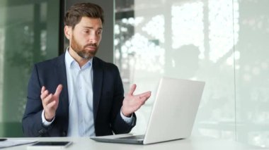 Ofisteki bir iş yerinde dizüstü bilgisayarla konuşan kendine güvenen bir iş adamı. Girişimcinin bir iş toplantısı var, uzaktan konuşuyor, çevrimiçi bir konferansta sohbet ediyor.