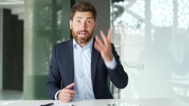 Webcam görüntüsü. Resmi takım elbiseli kızgın işadamı iş yerindeki iş yerinde kameraya bakarak tartışıyor. Heyecanlı erkek patron, astlarıyla sorunlar hakkında konuşuyor.