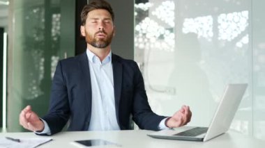 İş yerindeki iş yerinde otururken resmi takım elbiseli bir işadamı, kapalı gözlerle meditasyon yapıyor. Sakin ve yakışıklı bir işçi huzur içinde yatar. Erkek içeride yoga yapıyor.