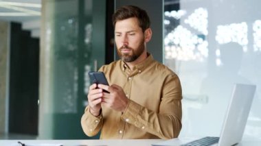 İş adamı, iş yerinde otururken akıllı telefon kullanıyordu. İşçi iletiyi okur veya yazar, bir istemciyle sohbet eder, cep telefonu uygulamasında bankacılık yapar, e- postaları kontrol eder veya çevrimiçi tarama yapar