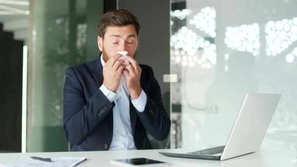 ビジネスオフィスのデスクに座っている間 季節のアレルギーに苦しむ正式なスーツのビジネスマン アレルギーの起業家はくしゃみをしてハンカチで鼻を拭きます — ストック動画