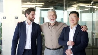 Portre dostu, olgun yetişkin yöneticiler ve yöneticilerden oluşan pozitif takım. Takım elbiseli kıdemli erkek işadamları, kurumsal yaştaki iş adamlarına poz veren kamera uzmanlarına bakıyor.