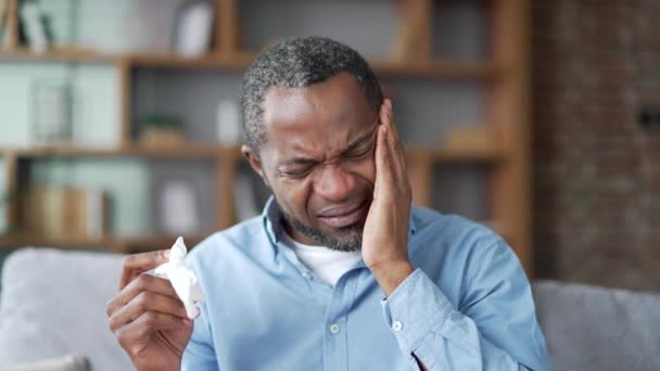 体弱多病的成熟的非洲裔美国男性 患有感冒和头痛 坐在家中客厅的沙发上 大胡子黑人男人用手帕擦鼻涕 他有发烧 病毒或流感 — 图库视频影像