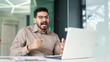 Kızgın hoşnutsuz işadamı iş yerindeki iş yerinde bilgisayarını kullanarak bir video görüşmesinde tartışıyor. Heyecanlı patron, çözülmesi gereken sorunlar hakkında duygusal olarak konuşur.