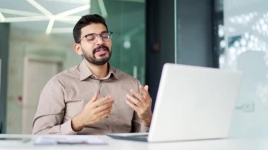 Kendine güvenen sakallı iş adamı iş yerindeki bir iş yerinde bilgisayarını kullanarak video görüşmesi yapıyor. Erkek bir koç uzaktan konuşur, çevrimiçi bir konferansta ya da Webinar 'da sohbet eder.