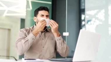 İş yerindeki bir masada otururken sezonluk alerjiden muzdarip hasta işadamı. Alerjik işçi hapşırır ve burnunu mendille siler. Virüs veya soğuk algınlığı var.