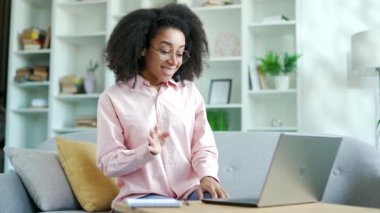 Genç Afro-Amerikan iş kadını, kablosuz kulaklıkla bilgisayarını kullanarak video konferansında konuşuyor. Kendine güvenen siyahi kadın koçun internet eğitimi ya da web sitesi var.