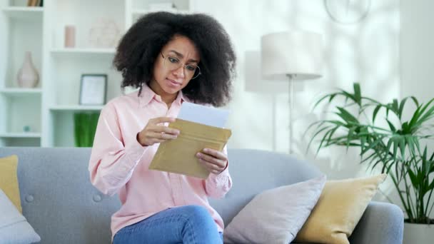 Zdenerwowana Młoda Afroamerykanka Czytająca List Złymi Wiadomościami Siedząca Kanapie Domu — Wideo stockowe