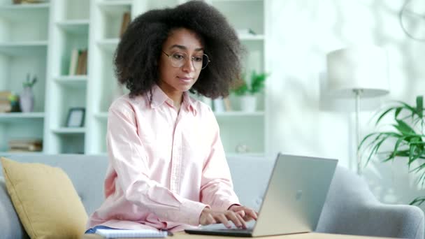 Молодая Африканка Фрилансер Работает Ноутбуке Сидя Диване Домашнем Офисе Счастливая — стоковое видео