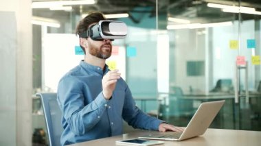 Kendine güvenen girişimci, iş yerindeki iş yerinde oturan sanal gerçeklik simülatöründe VR gözlükleri kullanır. İşçi bilgisayar programlarını kontrol etmek ve sanal sayfaları çevirmek için jestler kullanır