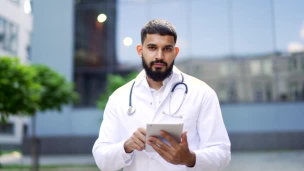 근처에 디지털 태블릿을 코트에 자신감 수염된 의사의 초상화 카메라를 청진기와 — 비디오