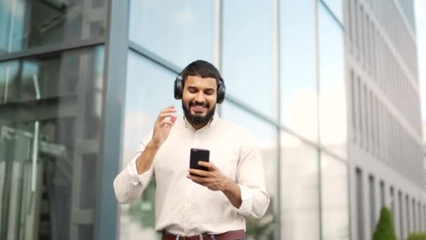 Mutlu Yakışıklı Çalışan Ofis Binasının Yanındaki Sokakta Yürürken Kablosuz Kulaklıkla — Stok video