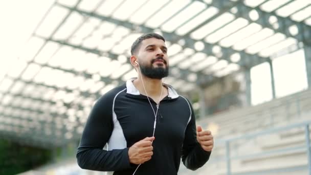 Homme Barbu Adulte Coureur Dans Casque Jogging Extérieur Dans Stade — Video