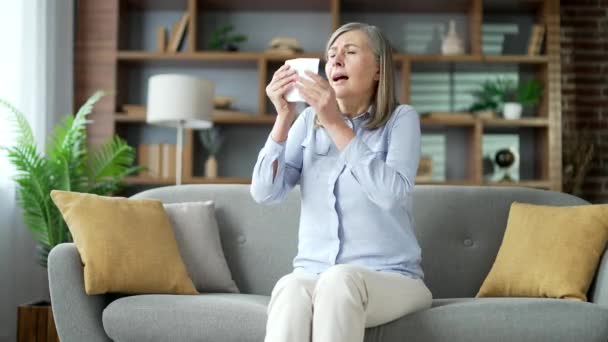 집에서 거실에서 소파에 알레르기 재채기를 알레르기 은퇴한 여자는 손수건으로 그녀의 — 비디오