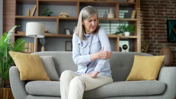 Mulher Sênior Com Cabelos Grisalhos Sofrendo Dor Cotovelo Sentado Sofá — Vídeo de Stock