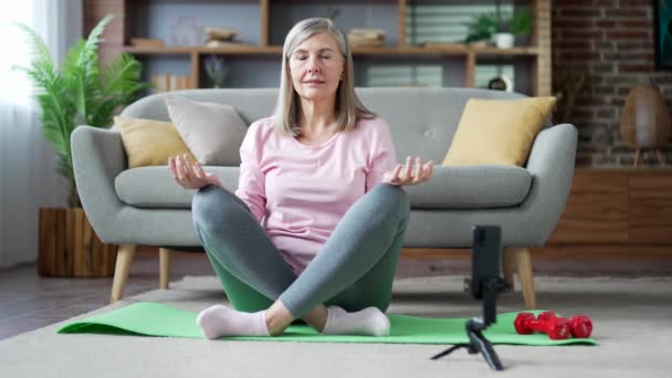 Senior Vrouw Mediteert Tijdens Een Online Cursus Aan Telefoon Terwijl — Stockvideo