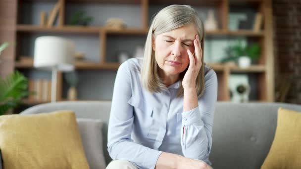 Senior Mujer Pelo Gris Que Sufre Dolor Cabeza Sentado Sofá — Vídeos de Stock