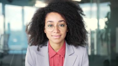 İş yerinde takım elbiseli Afro-Amerikan bir iş kadınının portresi. Gözlüklü, gülümseyen siyah kadın kameraya bakıyor. Pozitif kız öğrencinin vesikalığı. Kapat.