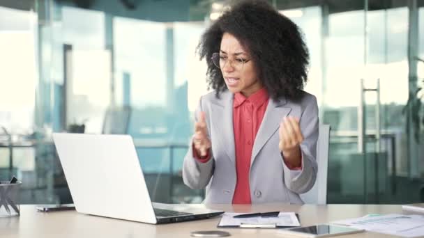 愤怒的非洲裔美国女商人坐在办公室的办公室里 一边用手提电脑对着一个视频通话一边争论 沮丧的黑人妇女与下属争吵描述问题 — 图库视频影像