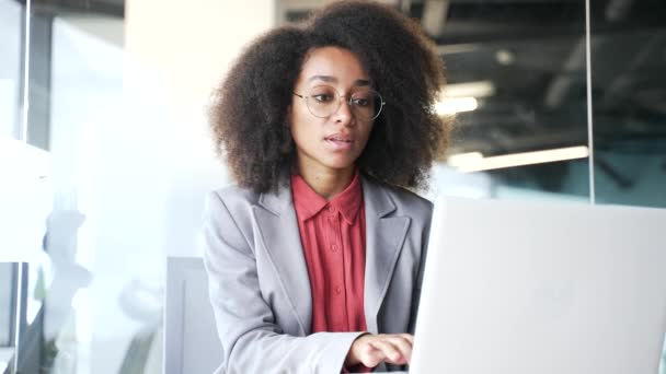 穿着夹克在办公室笔记本电脑上打字的年轻的非洲裔美国女商人 从事计算机应用 银行业务 发短信 网上聊天或忙于某个项目的黑人妇女 — 图库视频影像