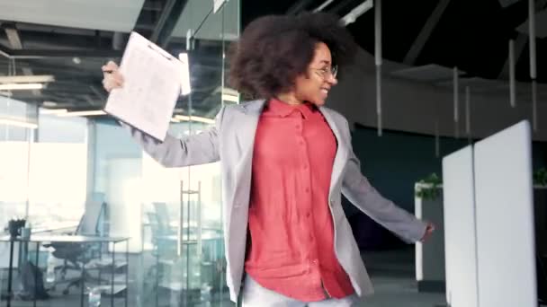 幸せな喜びの若いアフリカ系アメリカ人女性従業員は 現代のビジネスセンターの廊下やホールで勝利ダンスを踊ります おかしな興奮する黒人女性オフィスワーカー 明るく達成を祝う — ストック動画